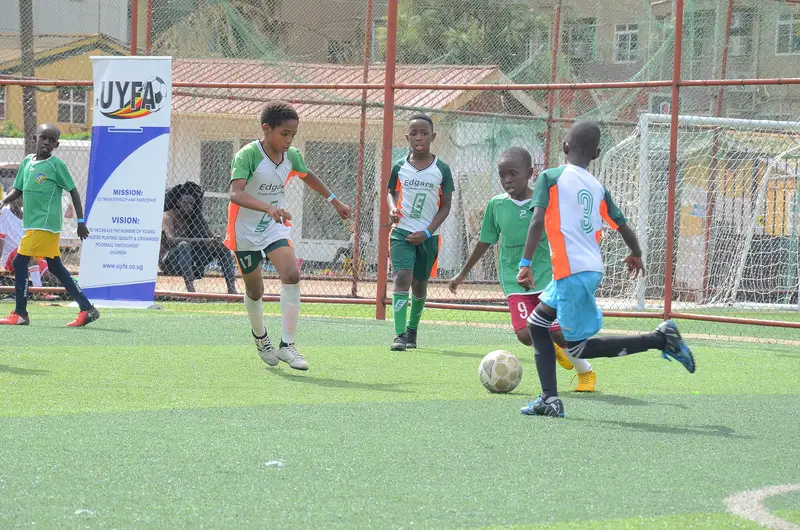 Anak-anak dari dua akademi sepak bola berebut bola di lapangan rumput sintetis dalam turnamen usia muda