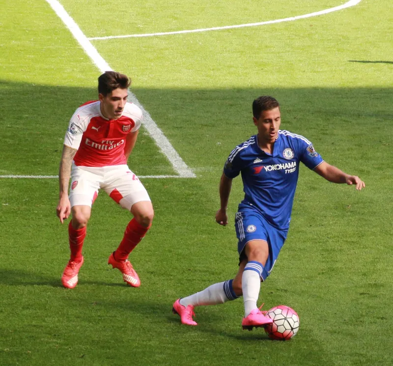 Eden Hazard berseragam Chelsea membawa bola sambil diawasi seorang bek Arsenal