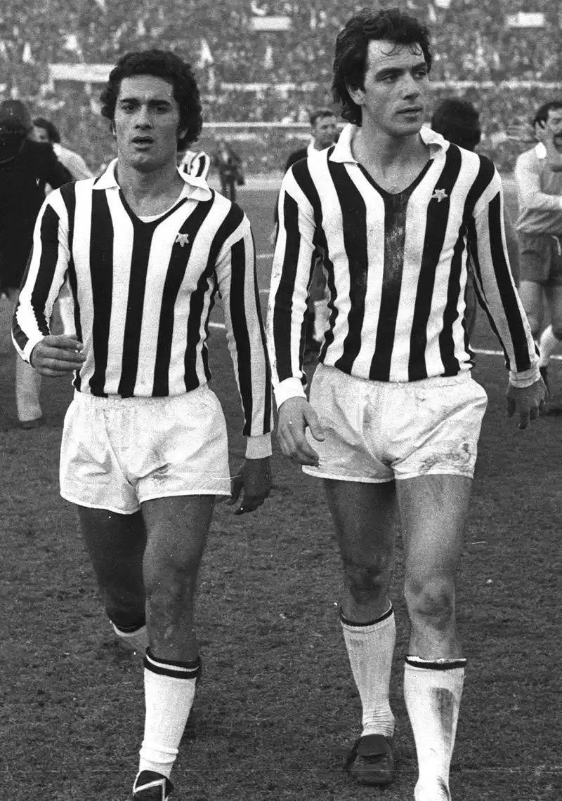 Dua pemain Juventus berseragam garis hitam putih berjalan meninggalkan lapangan dengan wajah kecewa