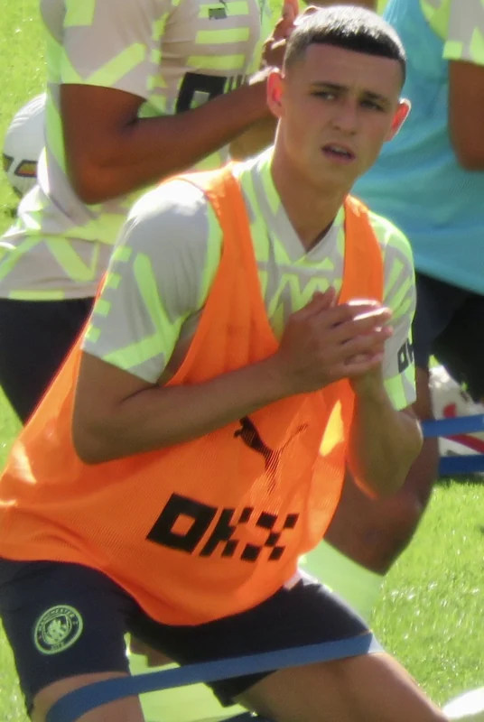 Phil Foden mengenakan rompi latihan di tepi lapangan
