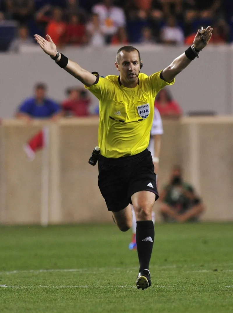 Wasit Mark Geiger memberi isyarat keuntungan