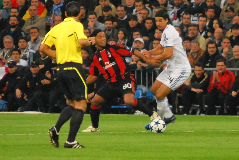 Ronaldinho berseragam AC Milan nomor 80 menguasai bola di depan Sami Khedira berseragam putih Real Madrid