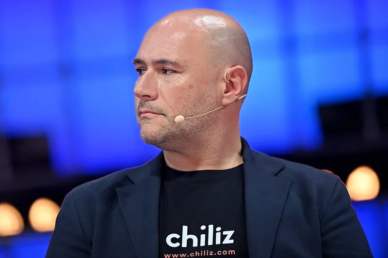 Alexandre Dreyfus memakai kaus hitam bertuliskan chiliz dan www.chiliz.com di panggung konferensi