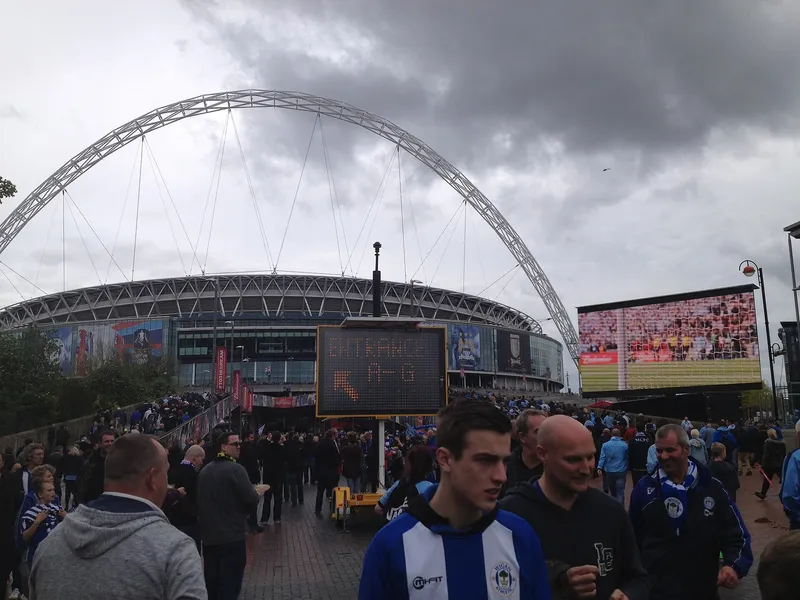 Pendukung Wigan berjersey biru putih berkumpul di luar Stadion Wembley dengan lengkung ikonik di belakangnya
