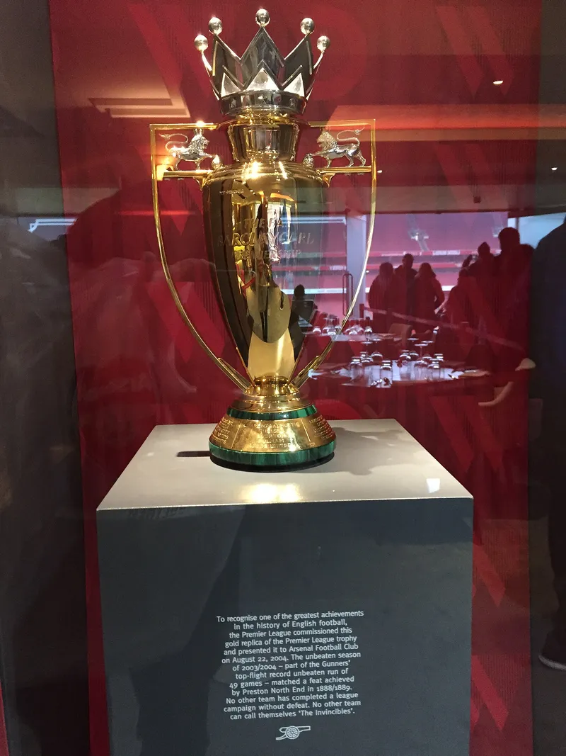 Replika emas trofi Liga Primer di dalam etalase kaca Emirates Stadium dengan plakat keterangan