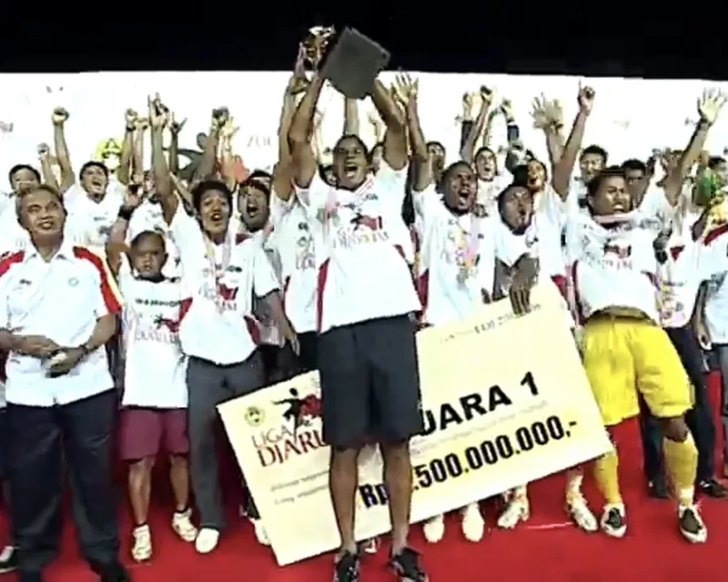 Pemain Sriwijaya FC berkaus putih mengangkat trofi dan papan hadiah juara 1 sambil bersorak