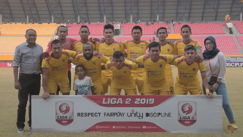 Skuad Sriwijaya FC berseragam kuning berfoto bersama di belakang spanduk Liga 2 2019