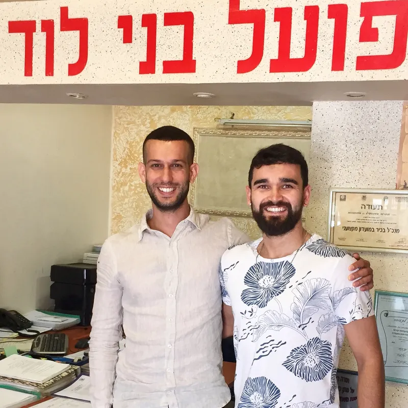 Seorang striker dan agennya berpose tersenyum di kantor klub Hapoel Bnei Lod