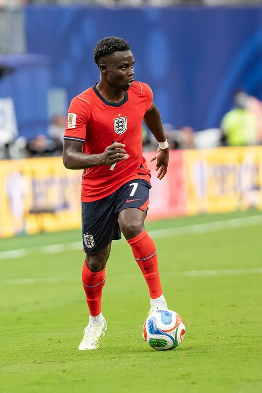 Bukayo Saka menggiring bola dengan seragam merah Inggris nomor 7.