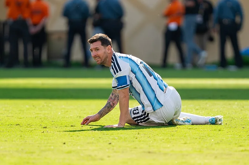 Lionel Messi duduk di rumput dengan seragam Argentina dan ban kapten.