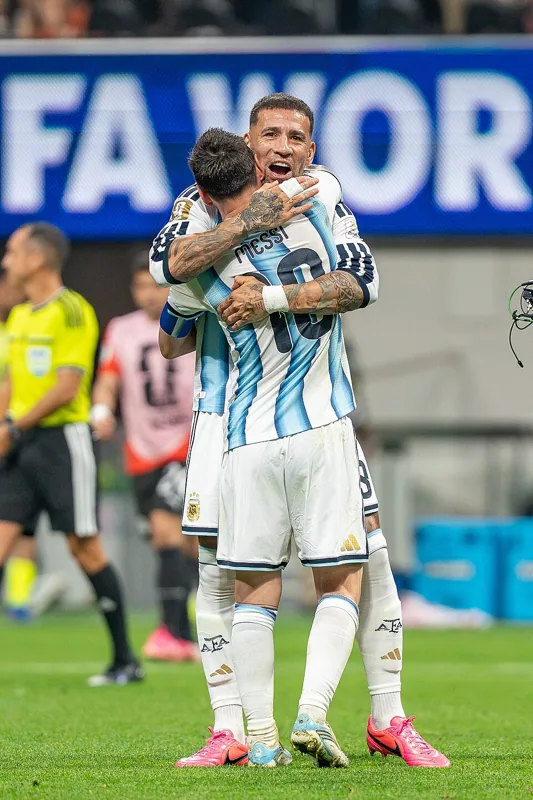 Lionel Messi berpelukan dengan Nicolás Otamendi dalam seragam Argentina.