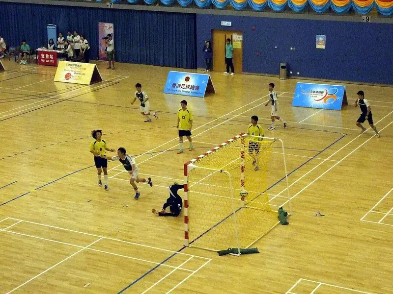 Gawang futsal bertiang merah putih berjaring kuning di lapangan indoor saat pertandingan